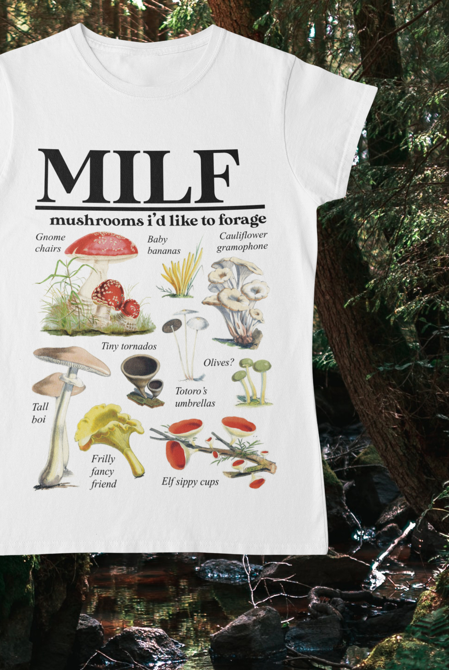 White tshirt which reads MILF Mushrooms I’d Like To Forage in a bold font at the top. Below this are 10 vintage mushroom illustrations with whimsical titles beneath them, e.g. tall boi and gnome chairs